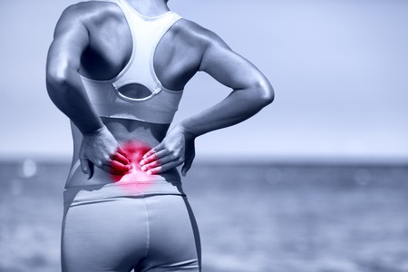 person standing with back arched and hands on lower back in pain